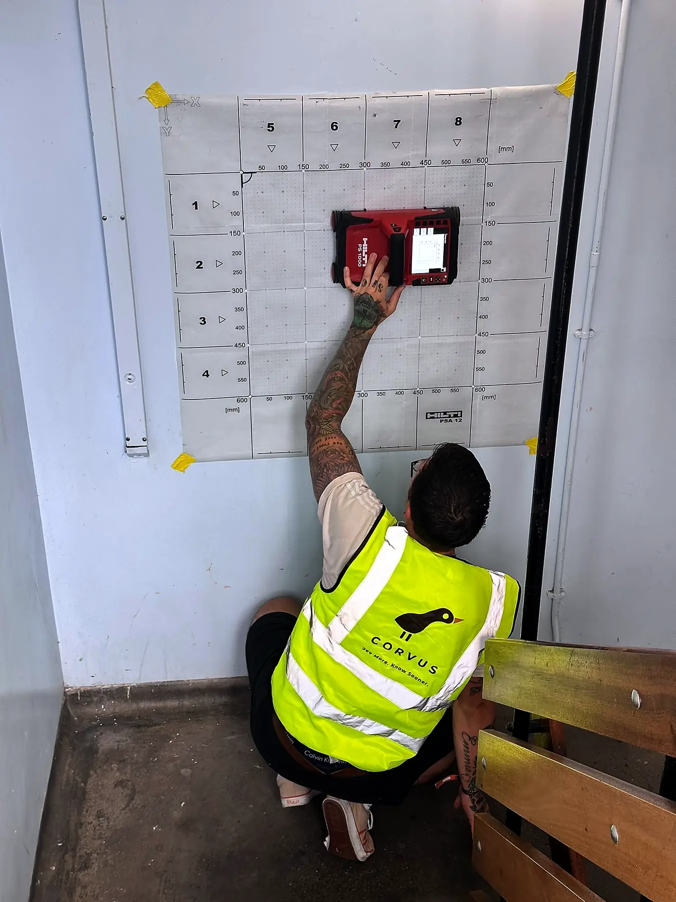 Corvus surveyor scanning a wall through a grid sheet to map reinforcement