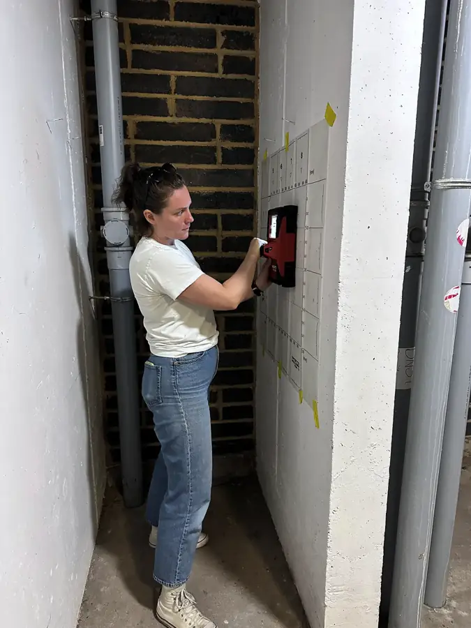 Surveyor scanning a stairwell wall in a high-rise residential block